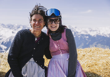 Zwei lachende Frauen sitzen auf einem Heuballen.