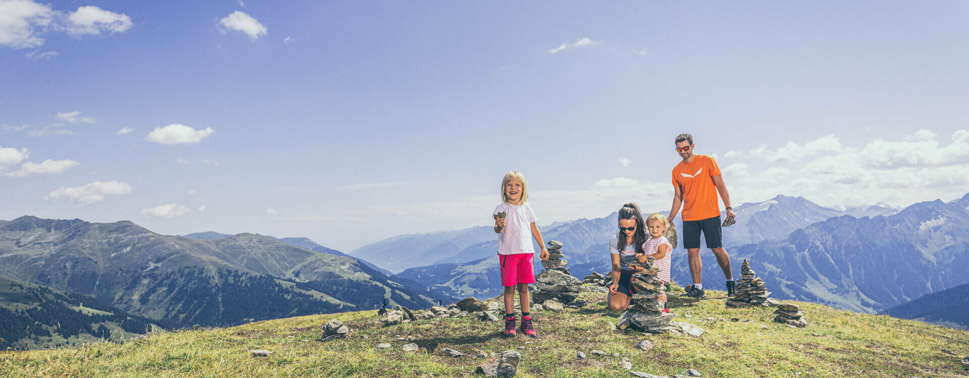 Eine Familie baut Steintürme vor einer traumhaften Bergkulisse