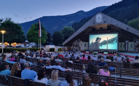 Sommerkino in Zell am Ziller am Musikpavillon, mit einem Film und einer Gruppe von Menschen auf Bänken
