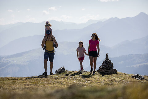 Ein Mann trägt ein kleines Mädchen auf seinen Schultern und eine Frau hält ein anderes Mädchen an der Hand