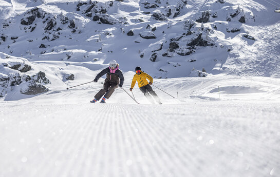 Zwei Skifahrer in verschneiter Pistenlandschaft