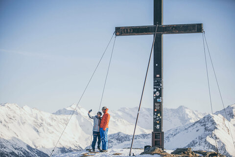 Ein Mann und eine Frau machen ein Selfie am Gipfelkreuz
