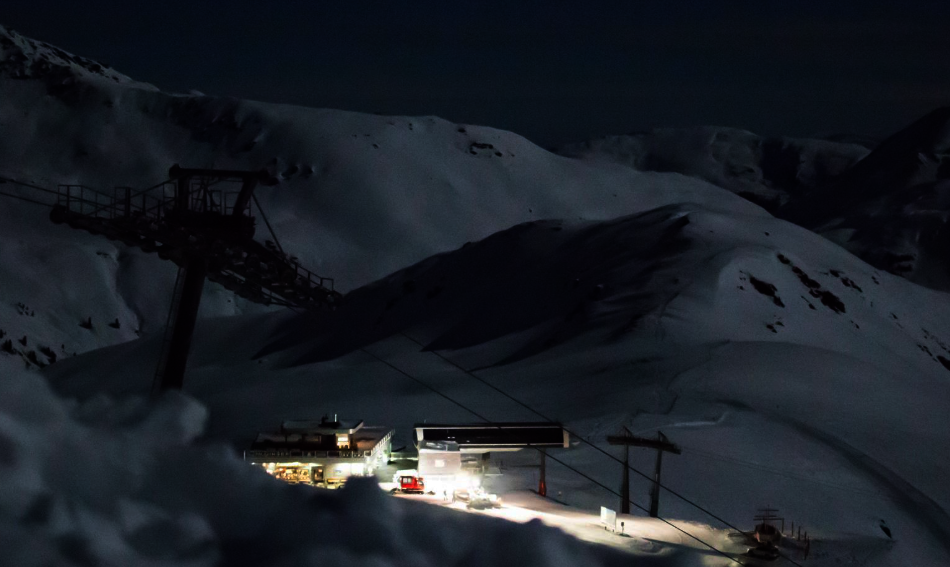 Blick auf eine verschneite Piste bei Nacht.