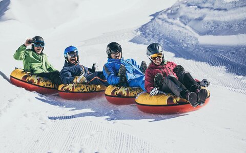 Vier Personen fahren auf luftgefüllten Reifen die Piste hinunter