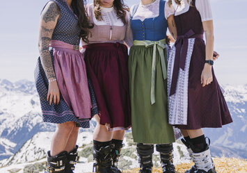 Vier Frauen in Dirndln stehen auf einem Heuballen.