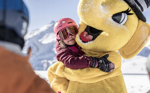 Ein kleines Mädchen umarmt das Maskottchen Funty