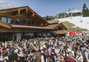 Eine große Gruppe von jungen Menschen feiern vor einem Haus.