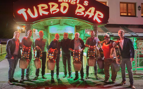 Männer posieren vor 'Luigis Turbo Bar'.