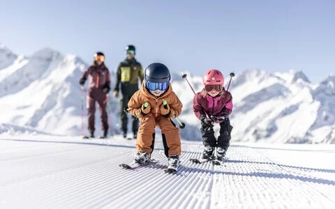 Zwei Kinder fahren auf Skiern über die Piste