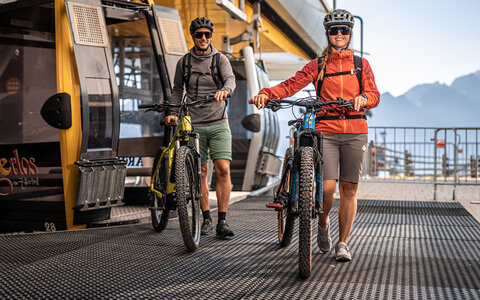 Zwei Radfahrer steigen aus einer Seilbahn aus