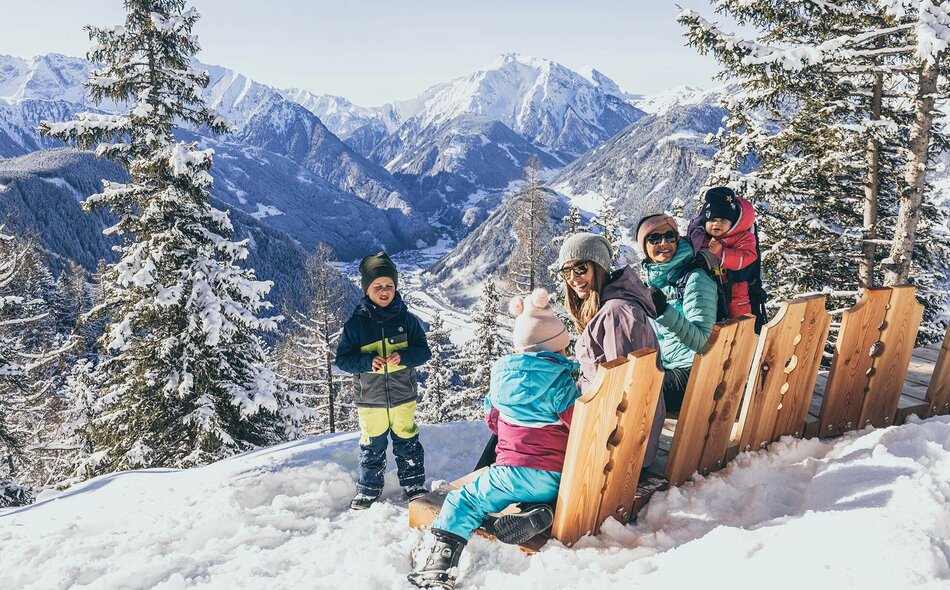 Zwei Frauen und drei Kinder sitzen vor einer traumhaften Bergkulisse