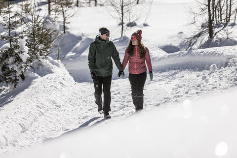 Ein Mann und eine Frau spazieren Hand in Hand durch den Schnee