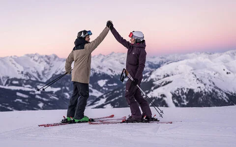 Zwei Skifahrer geben sich ein High-Five auf der Piste
