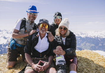 Zwei Männer und zwei Frauen sitzen zusammen auf einem großen Heuballen.
