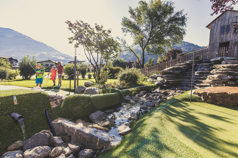 Eine Frau und zwei Kinder spielen Minigolf