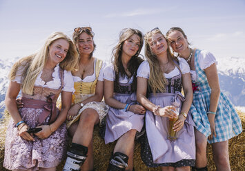Fünf Frauen in schönen Dirndln sitzen auf einem Heuballen.