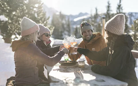 Ein Mann und drei Frauen stoßen mit einem Glas Wein an