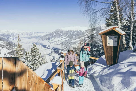 Zwei Frauen und drei Kinder spazieren durch den Schnee