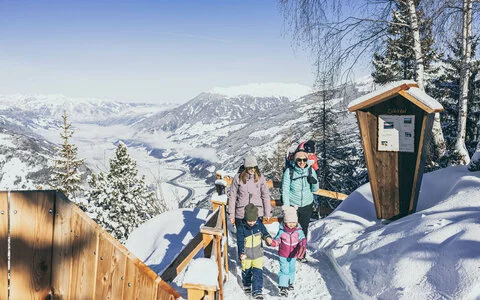 Zwei Frauen und drei Kinder spazieren durch den Schnee