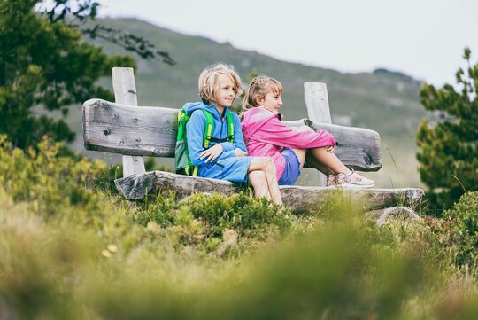 Zwei Kinder sitzen auf einer Holzbank
