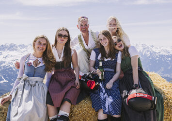 Sechs Frauen in Trachtenkleidung sitzen auf einem Heuballen.
