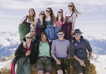 Eine zehnköpfige Gruppe sitzt zusammen auf einem Heuballen.