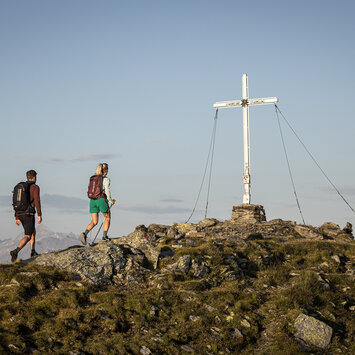 Ein Mann und eine Frau wandern zum Gipfelkreuz