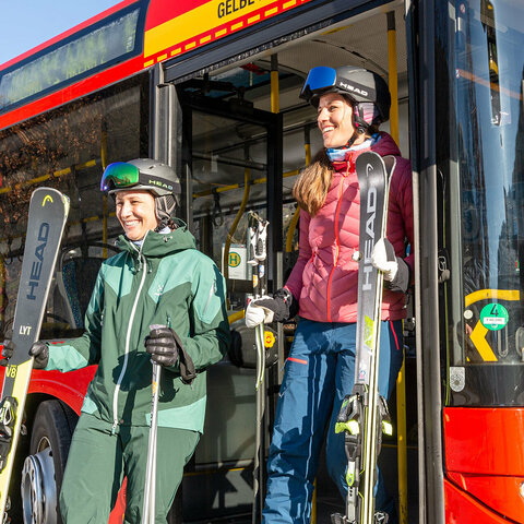 Skifahrer steigen aus einem roten Bus aus