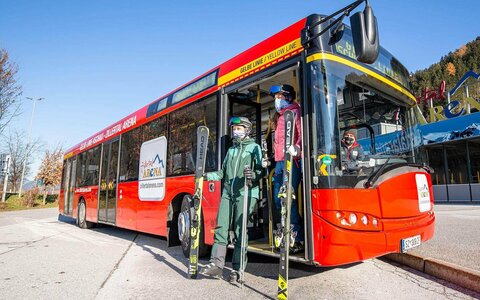 Skifahrer steigen aus einem roten Bus aus