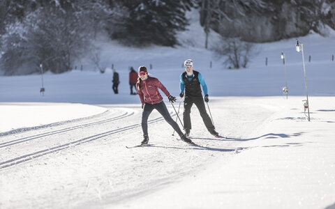 Zwei Langläufer auf einer verschneiten, sonnigen Strecke
