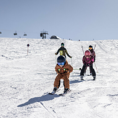 Zwei Kinder gleiten auf Skiern über die Piste