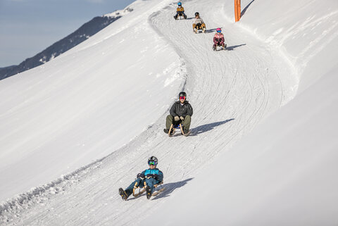 Rodler fahren die Strecke hinunter