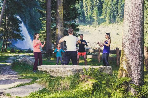 Ein Mann zeigt drei Frauen und einem Mädchen Entspannungstechniken