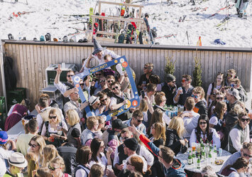 Eine Menschengruppe in Tracht feiert zusammen im Freien.