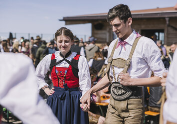 Ein Mann und eine Frau in Trachtenkleidung halten Händchen.