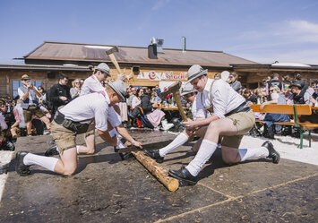 Eine Gruppe von Männern hacken und sägen an eine Stück Holz.