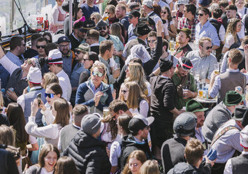 Junge Menschen in Tracht feiern zusammen im Freien.