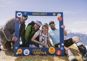 Drei Männer und eine Frau posieren mit einem Bilderrahmen.