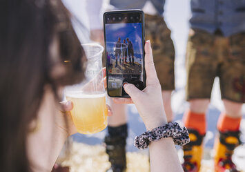 Eine Frau macht ein Foto von drei Männern in Tracht.