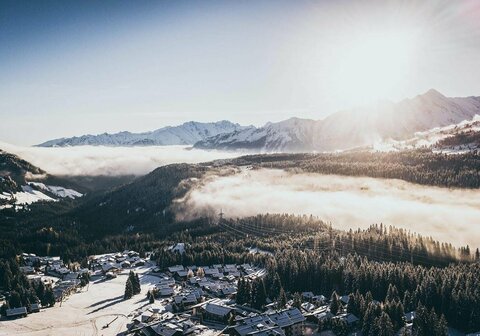 Blick auf eine traumhafte Winterlandschaft mit schneebedeckten Bäumen und einem klaren blauen Himmel