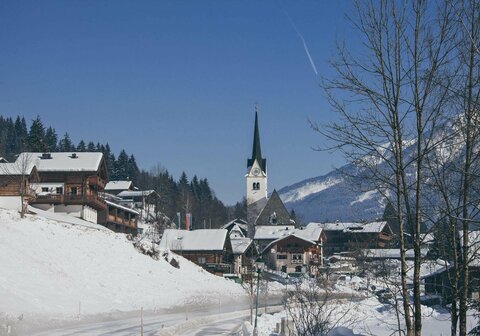 Blick auf ein schneebedecktes Dorf mit verschneiten Häusern und winterlichen Landschaften
