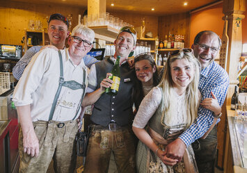 Sechs Personen in Tracht stehen hinter einer Bar.