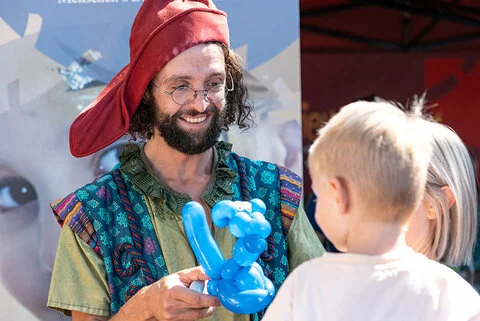 Ein Mann gibt einem Jungen ein Luftballontier.