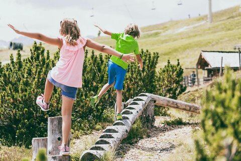 Ein Junge und ein Mädchen balancieren auf einem Holzstamm