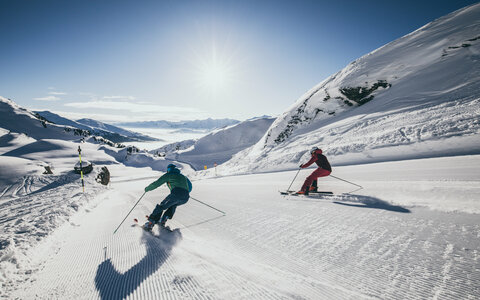 Skifahrer fahren eine Piste hinunter.