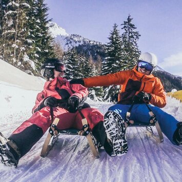 Zwei Rodler fahren die Strecke hinunter