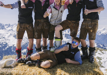 Junge Männer in Tracht posieren für ein Foto auf einem Heuballen.