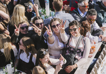 Frauen in Dirndln zeigen ein Peace Zeichen in die Kamera.