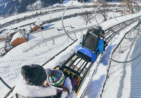 Eine Familie fährt auf der Winterrodelbahn
