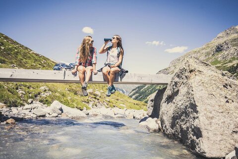 Zwei Frauen sitzen auf einer kleinen Holzbrücke